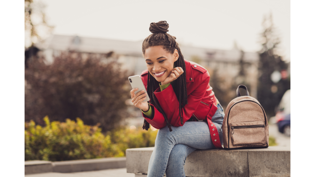 笑顔でスマホを見ながら石段に座る女性