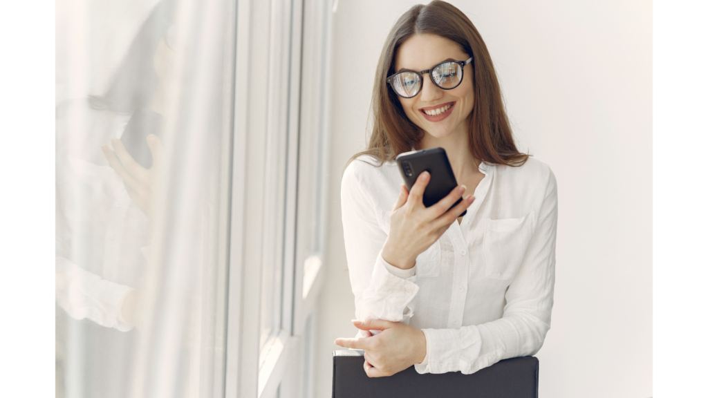 眼鏡をかけた女性がスマホを見て微笑む様子