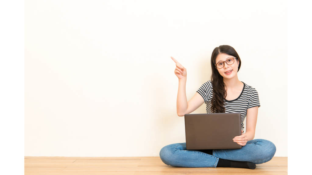 ノートPCを膝に置き、上を指さす女性