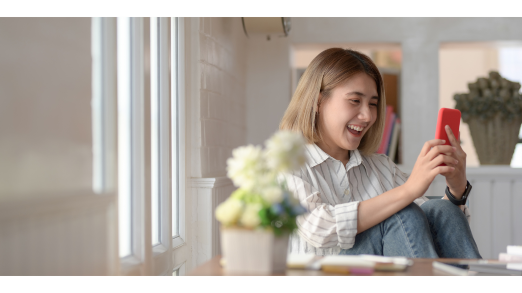 スマホを見ながら笑顔で座る女性